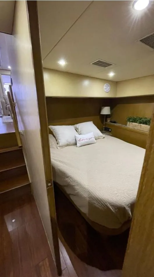 Slide: The Image of 1995 Bertram Convertible yacht bedroom with cozy bed, wooden interior, and soft lighting. - 43