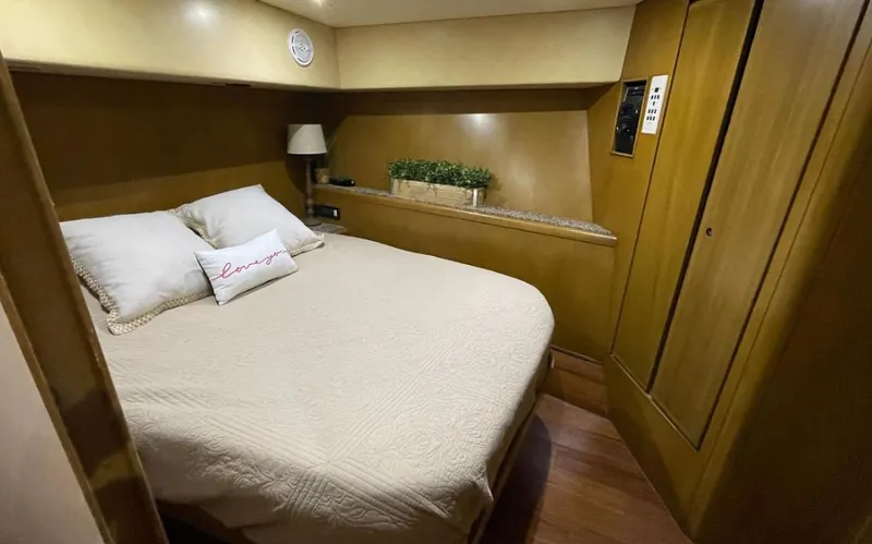 Slide: The Image of 1995 Bertram Convertible yacht bedroom with cozy bed, wooden cabinetry, and soft lighting. - 44