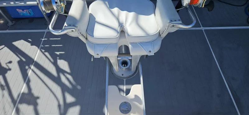 Slide: The Image of Captain's chair on a 1995 Bertram Convertible boat deck, featuring white upholstery and metal armrests. - 9
