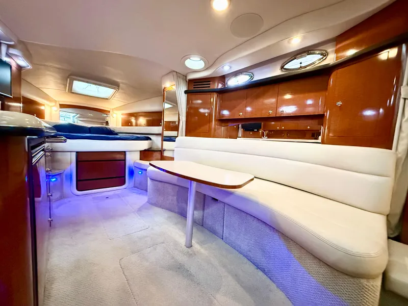 Slide: The Image of 2004 Sea Ray 340 Sundancer interior with white seating, wooden cabinets, and ambient lighting. - 22