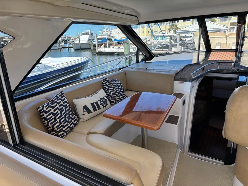 Slide: The Image of 2010 Regal 44 Sport Coupe interior with beige seating, wooden table, and decorative pillows in a marina setting. - 17