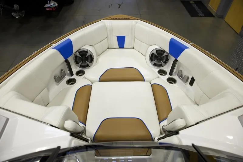 Slide: The Image of 2024 Malibu 23 LSV boat interior with white, blue, and brown seating, featuring cup holders and speakers. - 16