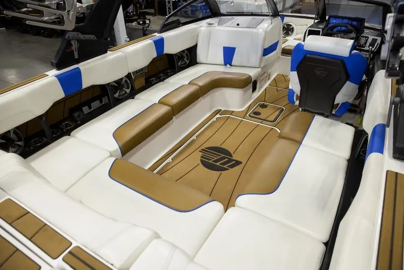 Slide: The Image of 2024 Malibu 23 LSV boat interior with white, blue, and brown seating and flooring. - 18