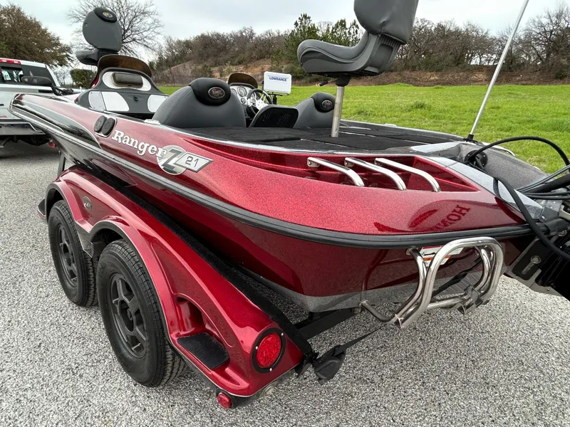 Slide: The Image of 2008 Ranger Z21 boat with red finish, dual seats, and trailer on gravel surface. - 15