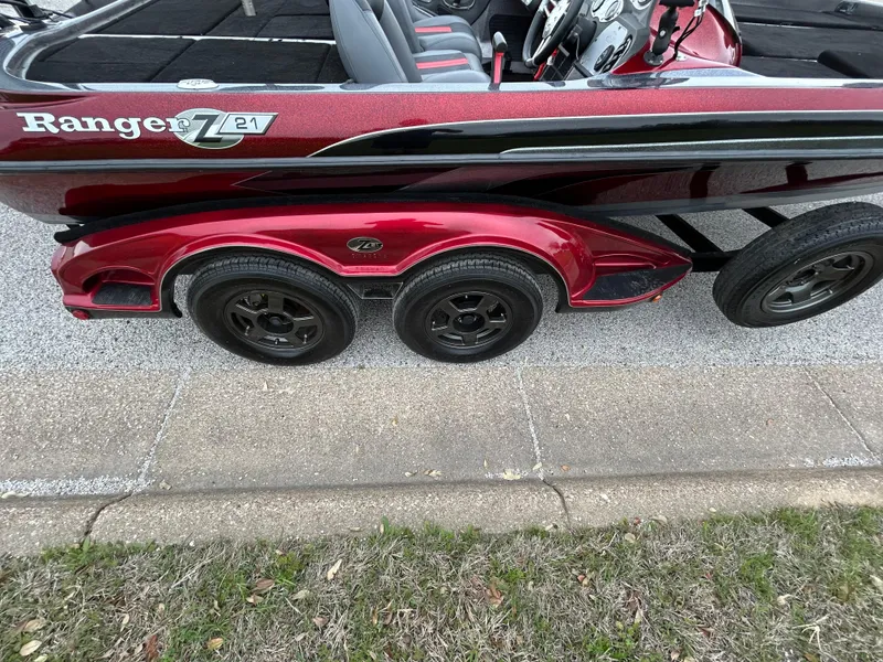 Slide: The Image of 2008 Ranger Z21 boat trailer with red finish and black wheels parked on pavement. - 17