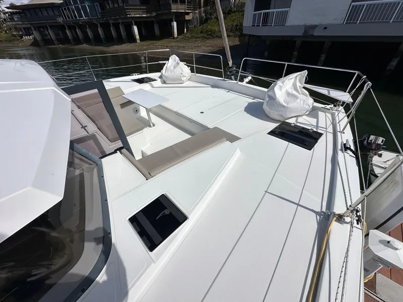 Slide: The Image of 2023 Bali 4.2 yacht deck with seating and hatches, docked near waterfront homes. - 21