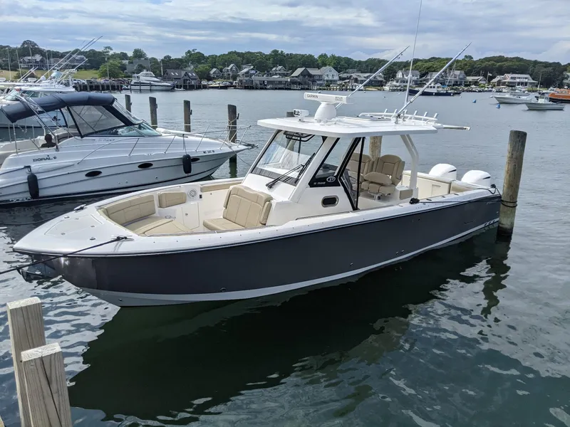 Slide: The Image of 2019 Pursuit S 328 Sport boat docked in a marina, featuring sleek design and spacious seating. - 0