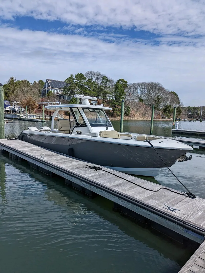 Slide: The Image of 2019 Pursuit S 328 Sport boat docked on a calm waterfront. - 1