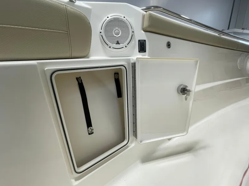 Slide: The Image of 2019 Pursuit S 328 Sport boat storage compartment with speaker and beige seating. - 12