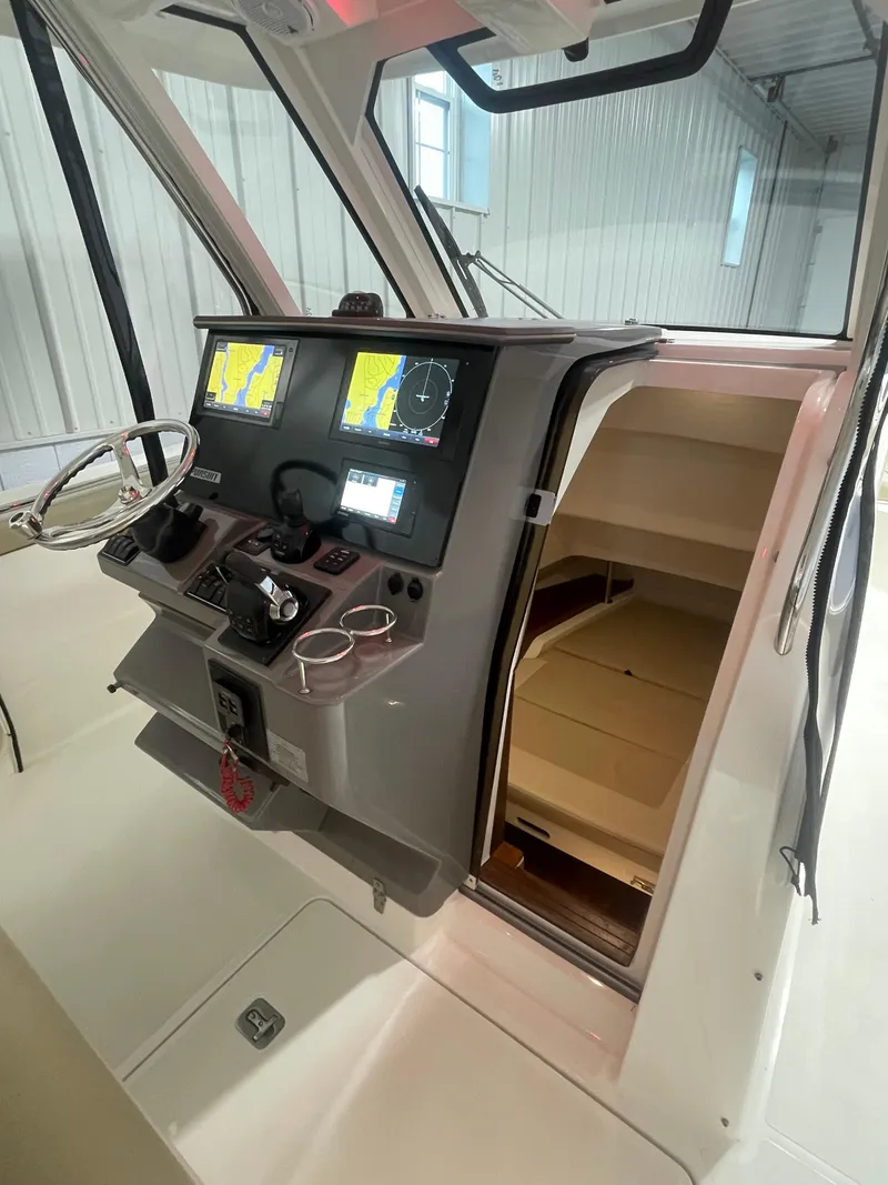 Slide: The Image of 2019 Pursuit S 328 Sport boat cockpit with navigation screens and cabin entrance. - 13
