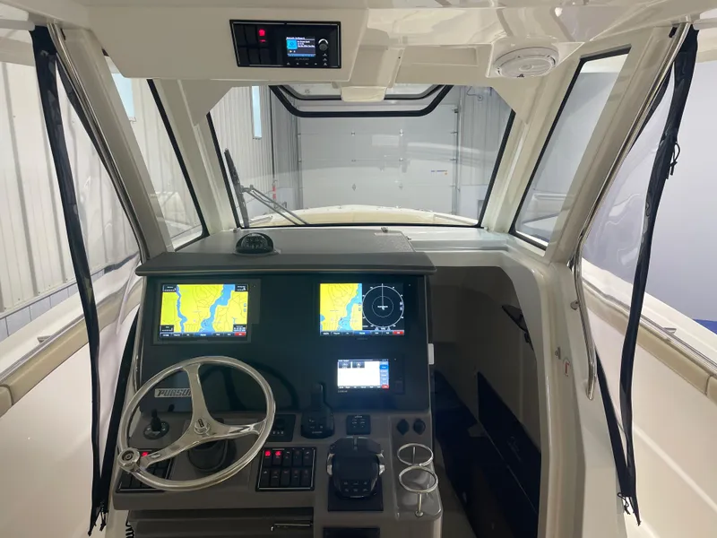 Slide: The Image of 2019 Pursuit S 328 Sport boat cockpit with navigation screens and steering wheel. - 15