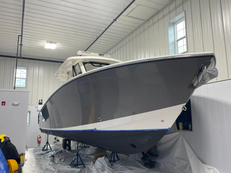 Slide: The Image of 2019 Pursuit S 328 Sport boat in indoor storage, elevated on stands. - 2