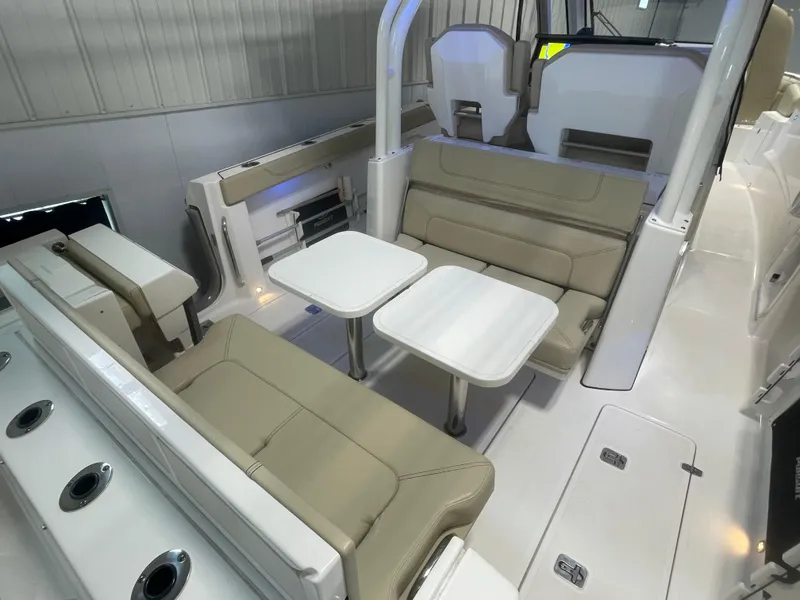 Slide: The Image of 2019 Pursuit S 328 Sport boat interior with beige seating and dual tables. - 34