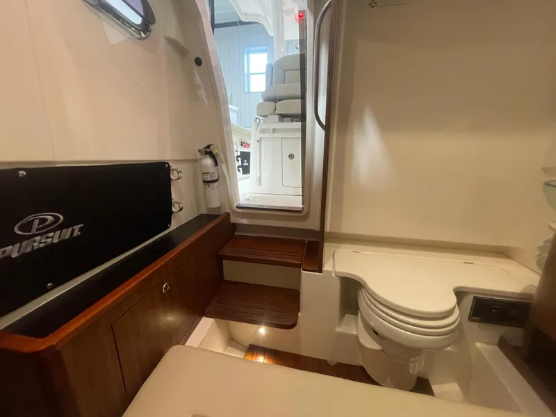 Slide: The Image of 2019 Pursuit S 328 Sport boat interior with wooden steps and compact bathroom. - 53