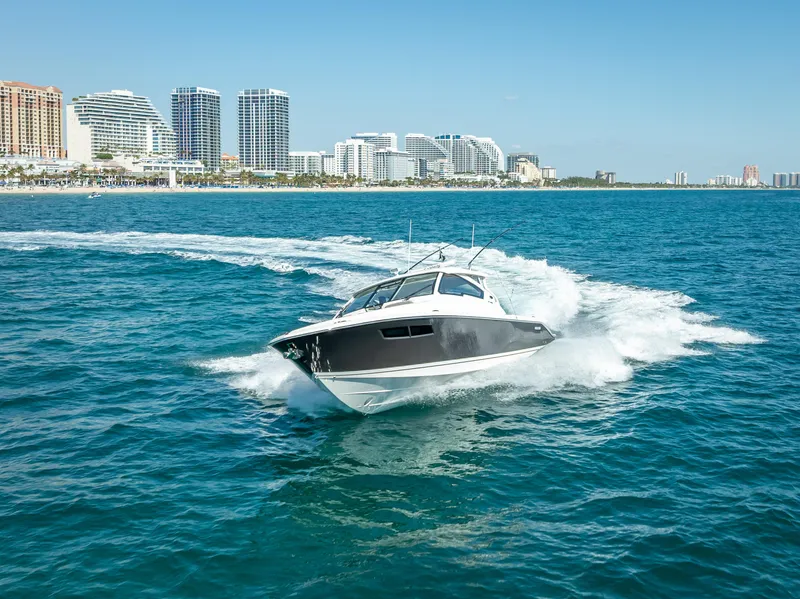Slide: The Image of 2022 Pursuit DC 365 Dual Console cruising on ocean near city skyline. - 2