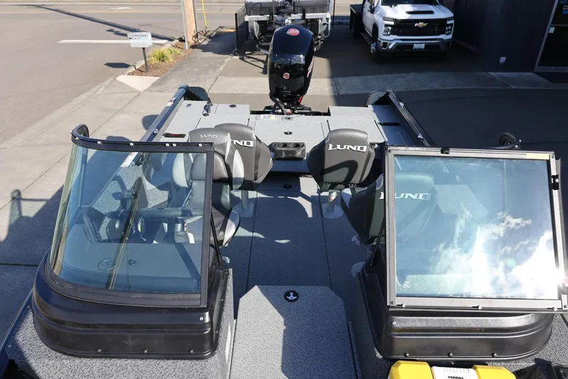 Slide: The Image of 2025 Lund 1875 Impact XS Sport boat with dual windshields and seating, parked outdoors. - 10