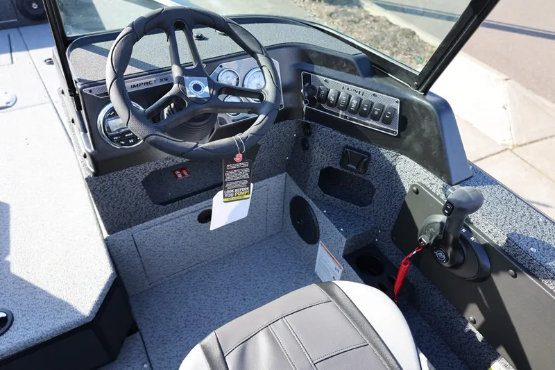 Slide: The Image of 2025 Lund 1875 Impact XS Sport boat cockpit with steering wheel and control panel. - 13