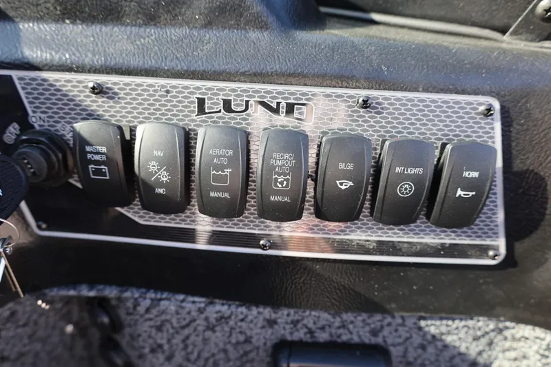 Slide: The Image of Control panel of 2025 Lund 1875 Impact XS Sport boat with labeled switches. - 14