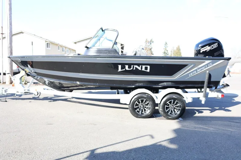 Slide: The Image of 2025 Lund 1875 Impact XS Sport boat on trailer, black exterior, side view. - 2