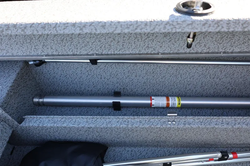 Slide: The Image of Storage compartment of 2025 Lund 1875 Impact XS Sport boat, featuring fishing rod holders. - 23