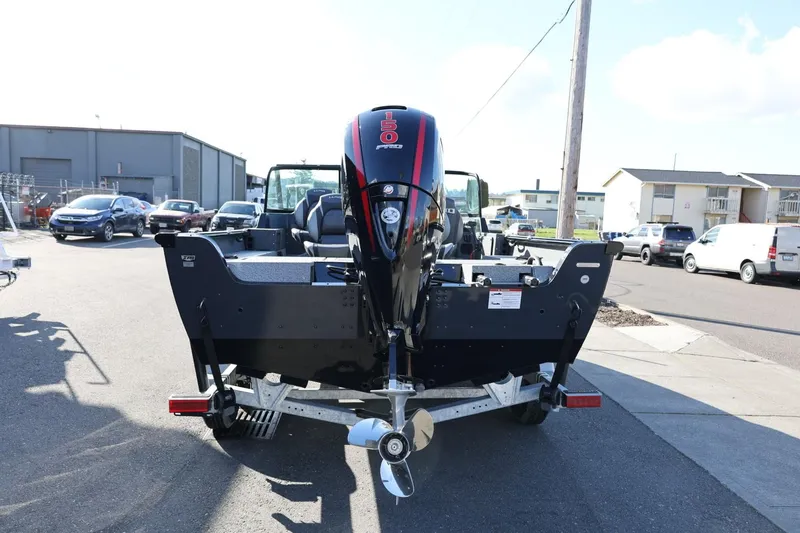 Slide: The Image of 2025 Lund 1875 Impact XS Sport boat, rear view with outboard motor, parked outdoors. - 7