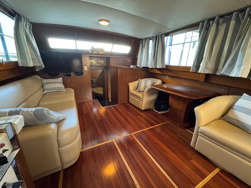Slide: The Image of 1964 Chris-Craft Roamer 46 interior with wood flooring, beige seating, and large windows. - 21