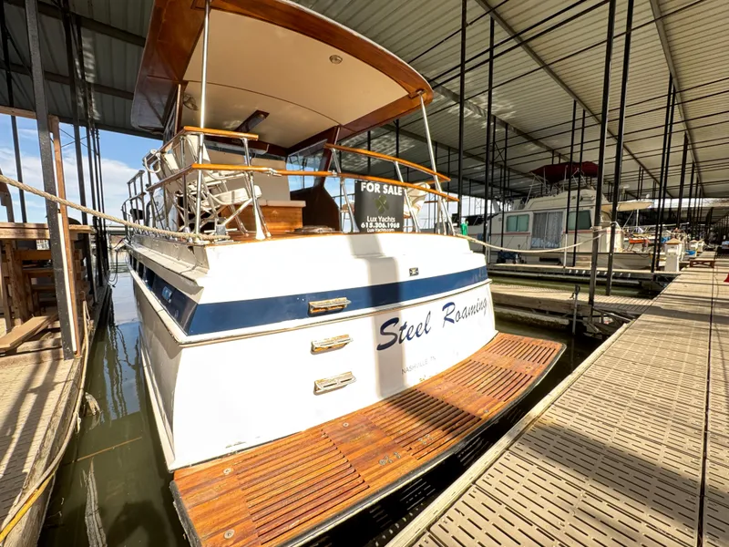 Slide: The Image of 1964 Chris-Craft Roamer 46 yacht docked, for sale, with wooden deck and covered marina. - 4