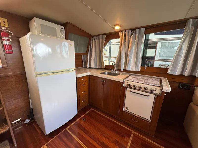 Slide: The Image of 1964 Chris-Craft Roamer 46 yacht kitchen with wood cabinetry, stove, and refrigerator. - 23