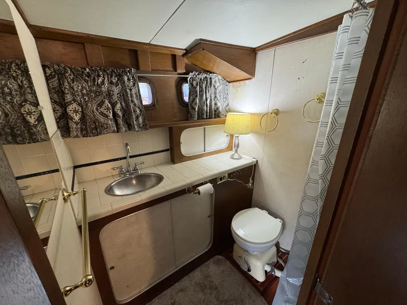 Slide: The Image of 1964 Chris-Craft Roamer 46 yacht bathroom with sink, toilet, and shower curtain. - 28