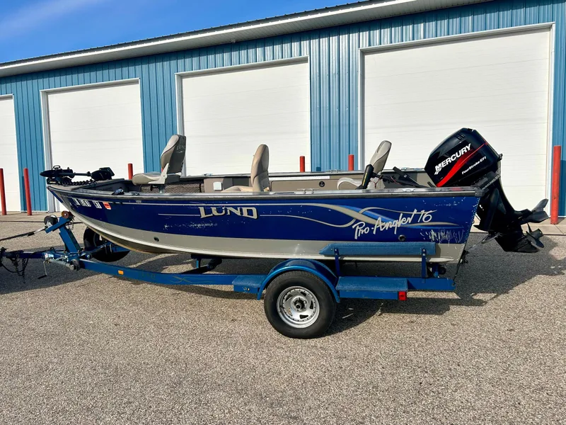 Slide: The Image of 2002 Lund Pro Angler 16 boat with Mercury outboard motor, parked on a trailer. - 1