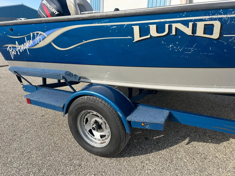 Slide: The Image of 2002 Lund Pro Angler 16 boat on trailer, blue exterior, parked on asphalt. - 9