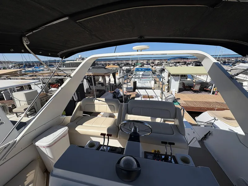 Slide: The Image of 1994 Carver 380 Santego yacht interior view at marina, showcasing helm and seating area. - 11
