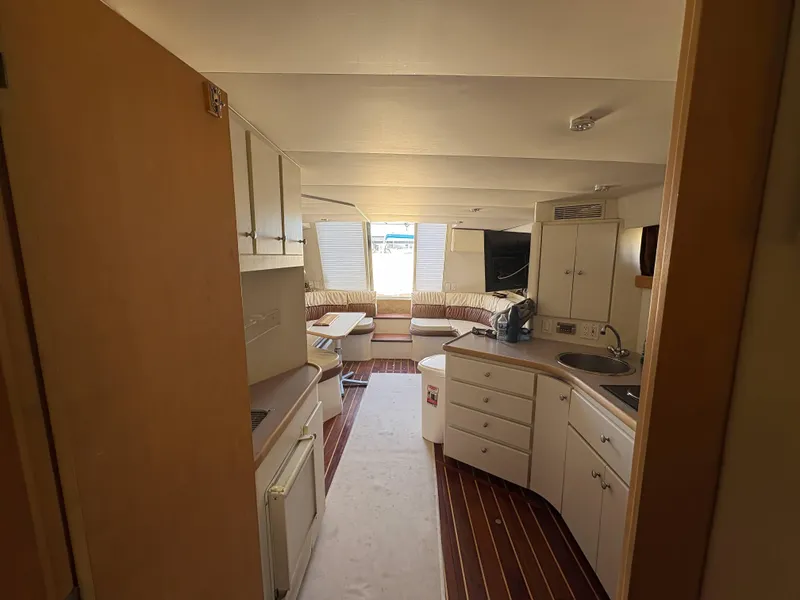 Slide: The Image of Interior of 1994 Carver 380 Santego yacht, featuring kitchen and seating area. - 13