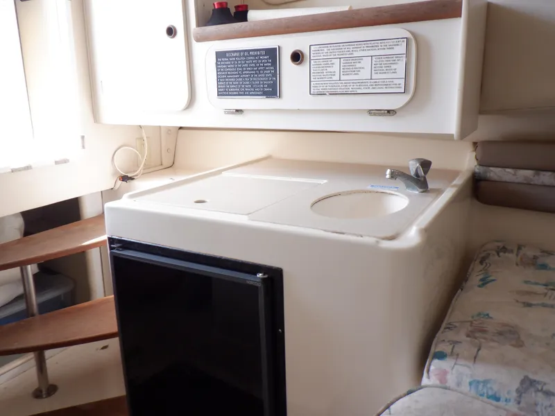 Slide: The Image of Interior of 1999 Pursuit 2870 Walkaround boat with compact kitchenette and seating area. - 11