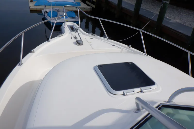 Slide: The Image of 1999 Pursuit 2870 Walkaround boat deck with hatch, docked by the water. - 12