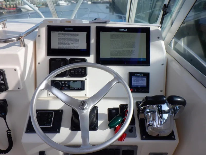 Slide: The Image of 1999 Pursuit 2870 Walkaround boat dashboard with steering wheel and navigation screens. - 13