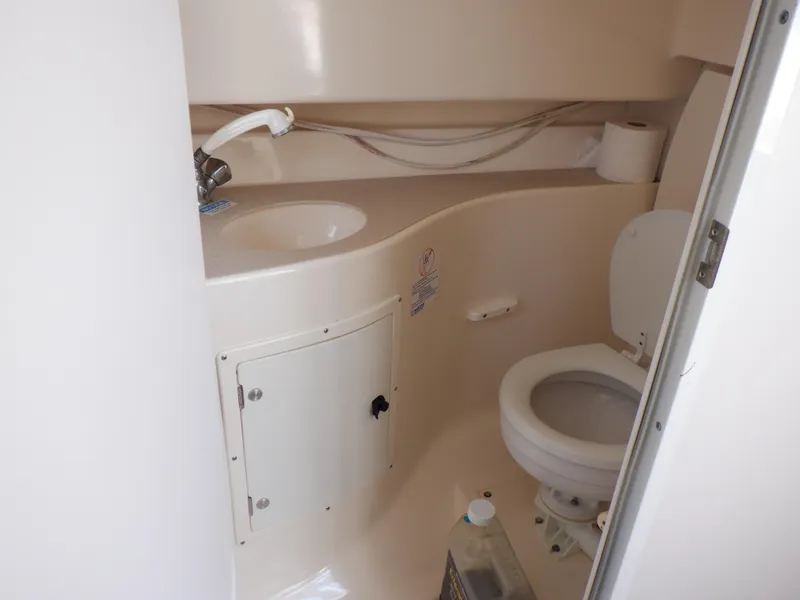 Slide: The Image of 1999 Pursuit 2870 Walkaround boat bathroom with sink, toilet, and storage compartment. - 9