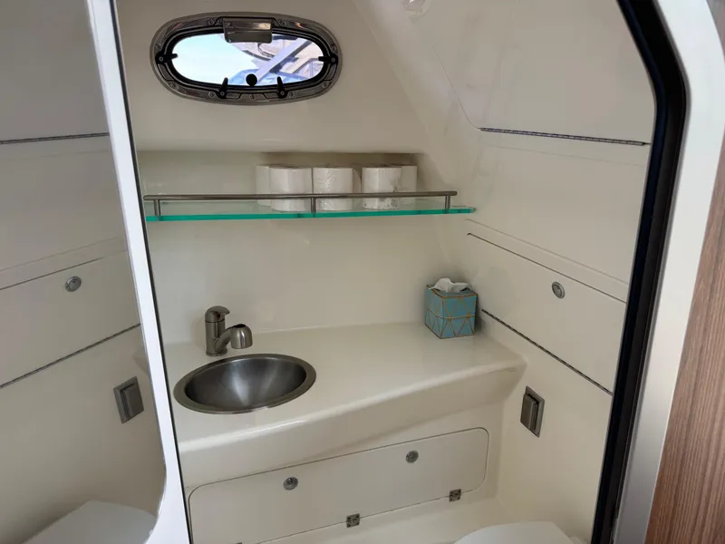 Slide: The Image of 2022 Boston Whaler 285 Conquest bathroom interior with sink, window, and storage. - 11