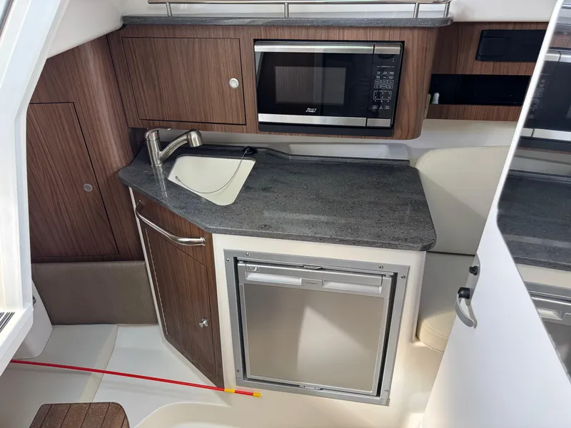Slide: The Image of 2022 Boston Whaler 285 Conquest galley with sink, microwave, and refrigerator. - 12