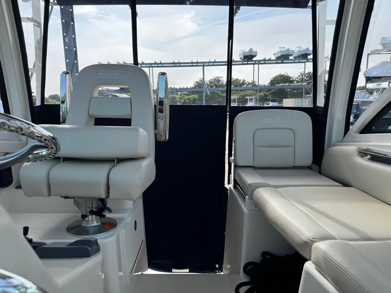 Slide: The Image of 2022 Boston Whaler 285 Conquest interior with white seating and steering wheel. - 14