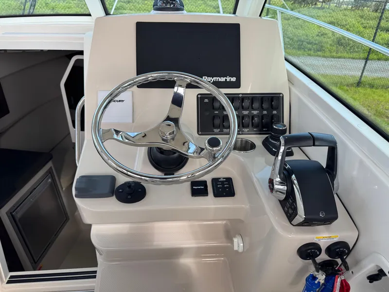 Slide: The Image of 2022 Boston Whaler 285 Conquest helm with steering wheel and control panel. - 16