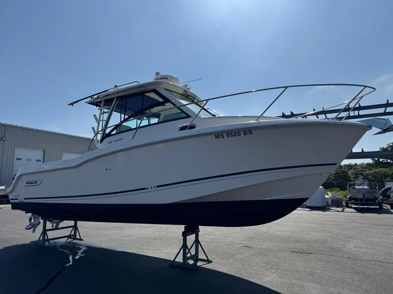 Slide: The Image of 2022 Boston Whaler 285 Conquest boat on stands, outdoor setting, clear sky. - 2