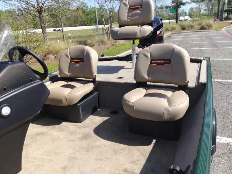 Slide: The Image of 2025 Tracker Bass Tracker Classic Limited boat with three cushioned seats in a parking area. - 10