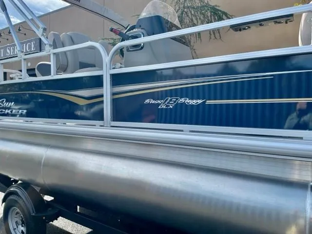 Slide: The Image of 2025 Sun Tracker Bass Buggy 18 DLX pontoon boat, side view with blue and silver design. - 1