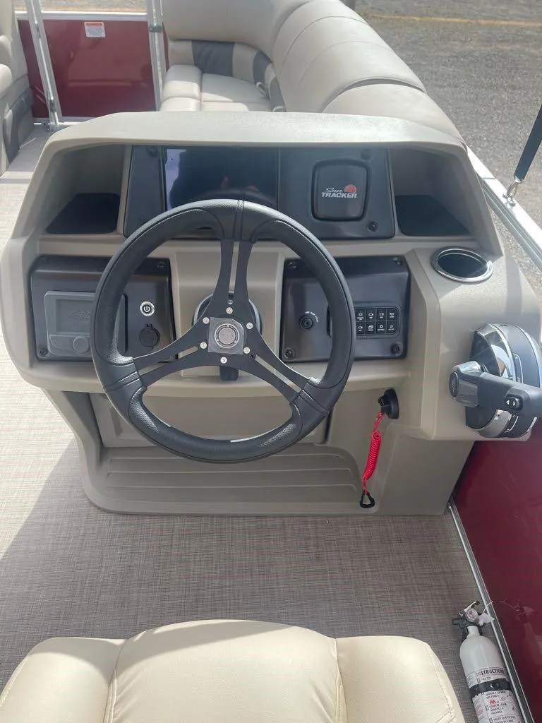 Slide: The Image of 2025 Sun Tracker Party Barge 20 DLX steering console with modern controls and beige seating. - 4
