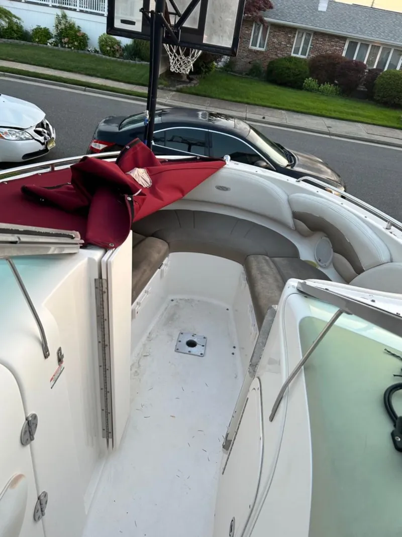 Slide: The Image of 2004 Chaparral 230 SSi boat interior with seating and red cover, parked on street. - 8