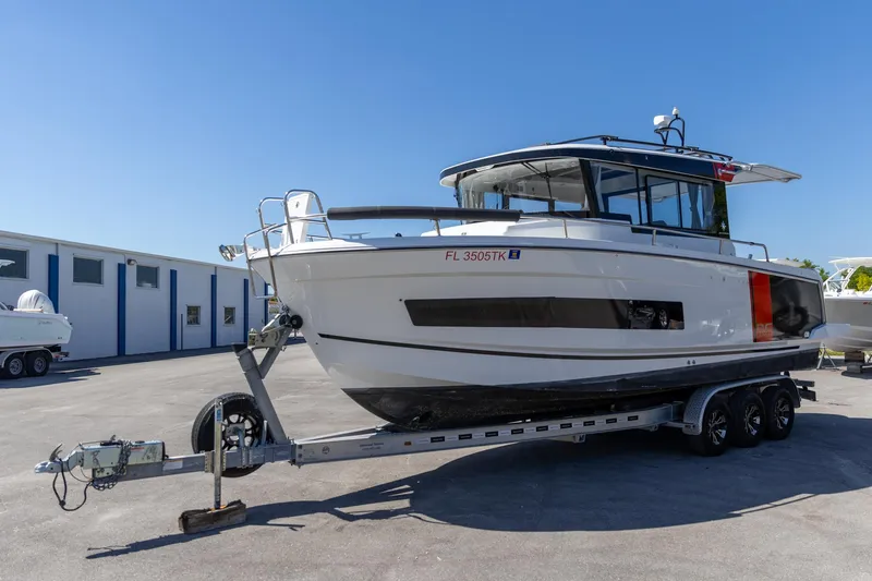 Slide: The Image of 2022 Jeanneau NC Sport 895 boat on trailer, parked outdoors under clear blue sky. - 11