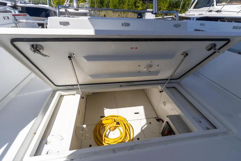 Slide: The Image of Open storage compartment on 2022 Jeanneau NC Sport 895 boat with yellow cable inside. - 6