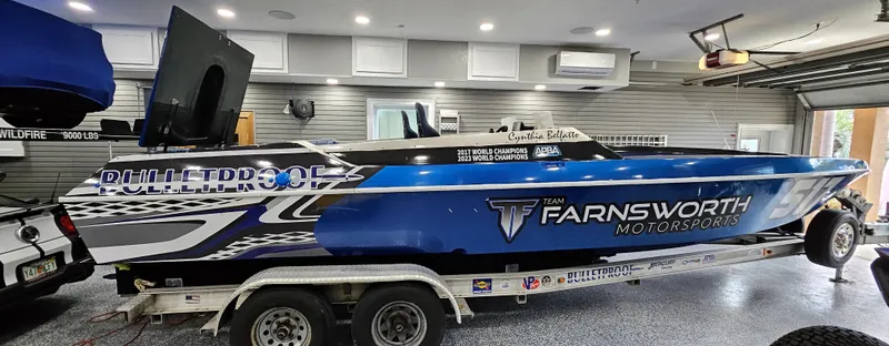 Slide: The Image of 2003 Ultimate Warlock 29 World Class Offshore Race boat in garage, blue and white design. - 6