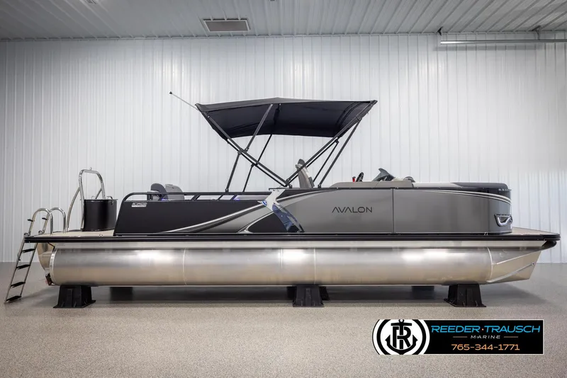 Slide: The Image of 2025 Avalon LSZ Vrl pontoon boat in showroom with canopy and sleek design. - 5